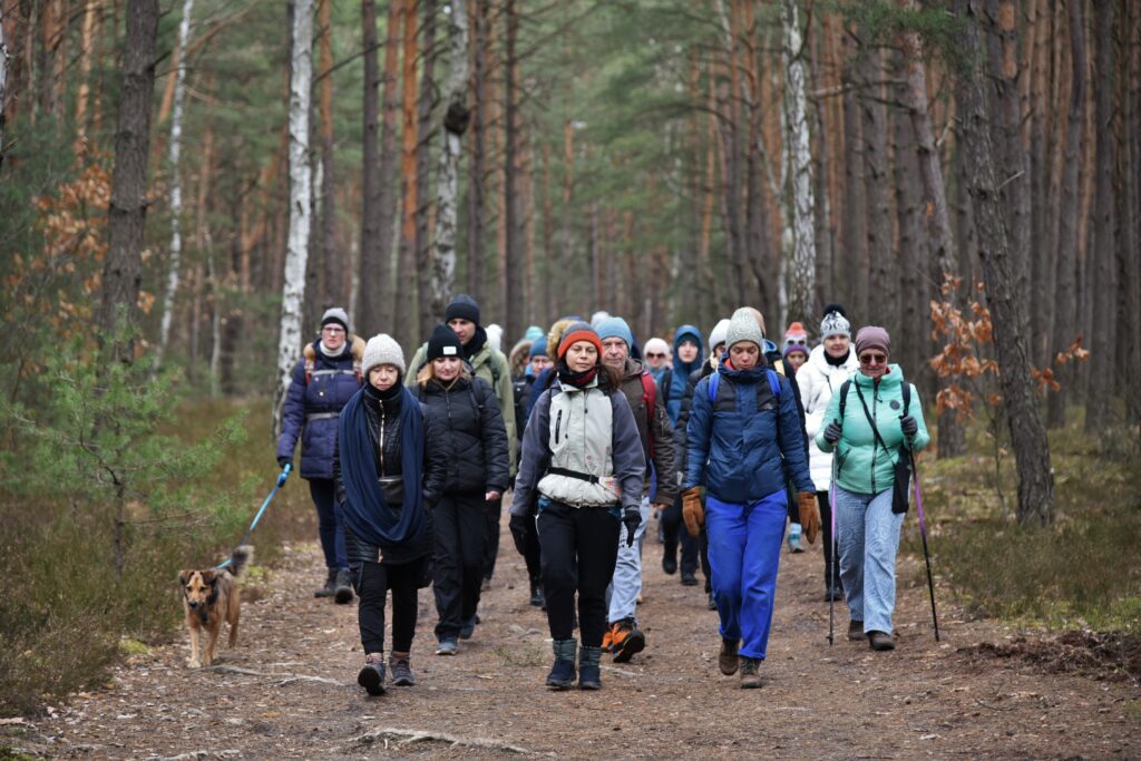 Grupa ludzi idących przez las. 